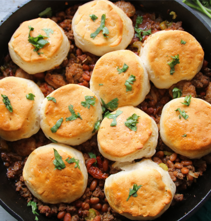 Cure-All One-Pan Comfort Skillet with beef, sausage, maple beans, and golden biscuits in a cast-iron pan
