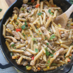 Ground beef kitchen sink pasta skillet with mixed vegetables and melted cheese in a cast iron pan