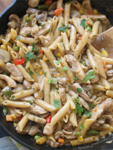 Ground beef kitchen sink pasta skillet with mixed vegetables and melted cheese in a cast iron pan