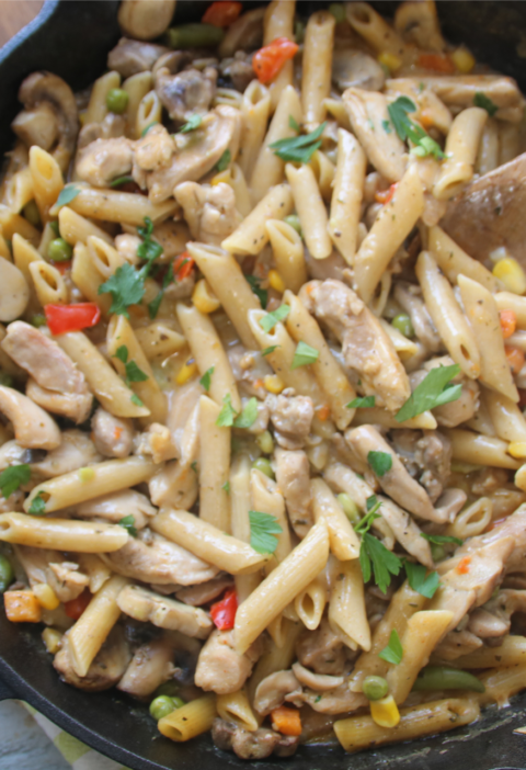 Ground beef kitchen sink pasta skillet with mixed vegetables and melted cheese in a cast iron pan