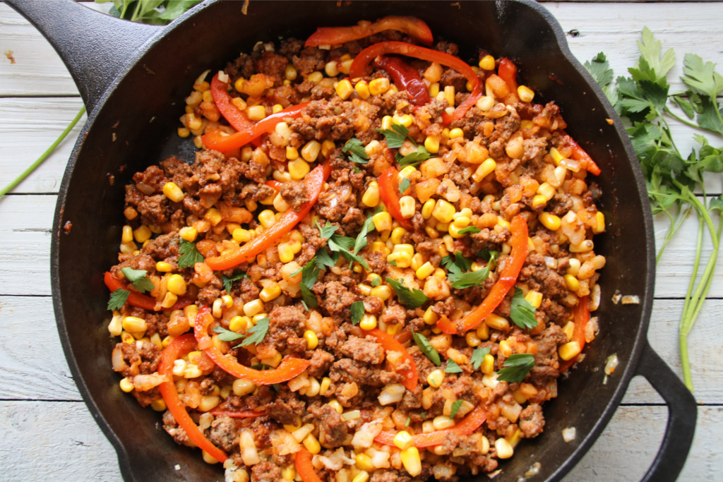 Smoky BBQ ground beef hash cooked in a skillet with potatoes and corn