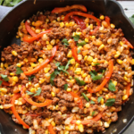 Smoky BBQ ground beef hash cooked in a skillet with potatoes and corn