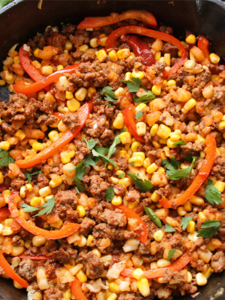 Smoky BBQ ground beef hash cooked in a skillet with potatoes and corn