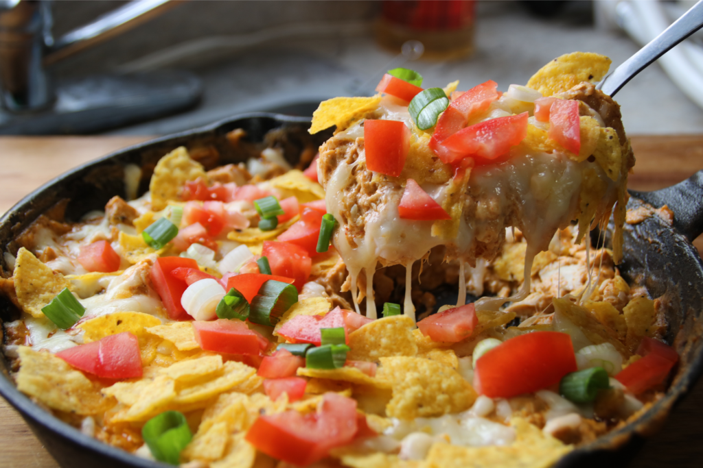 Creamy chicken nacho skillet with melted cheese, shredded chicken, and corn chips in a pan