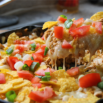 Creamy chicken nacho skillet with melted cheese, shredded chicken, and corn chips in a pan