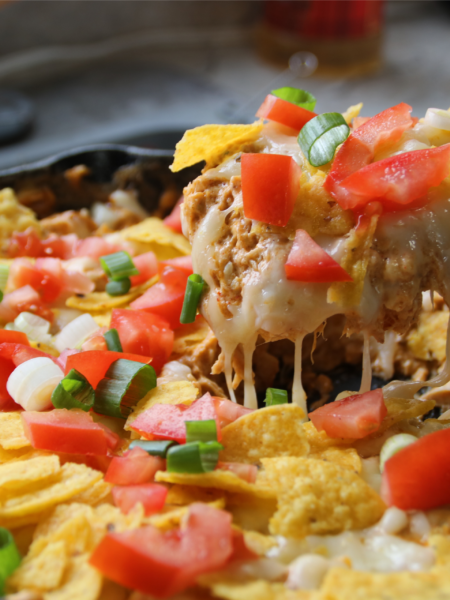 Creamy chicken nacho skillet with melted cheese, shredded chicken, and corn chips in a pan