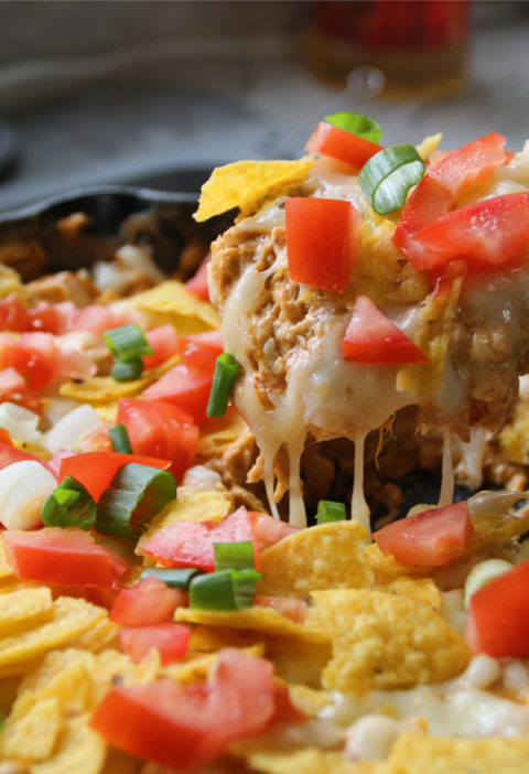 Creamy chicken nacho skillet with melted cheese, shredded chicken, and corn chips in a pan