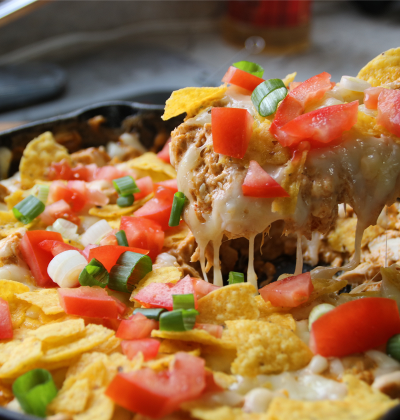 Creamy chicken nacho skillet with melted cheese, shredded chicken, and corn chips in a pan