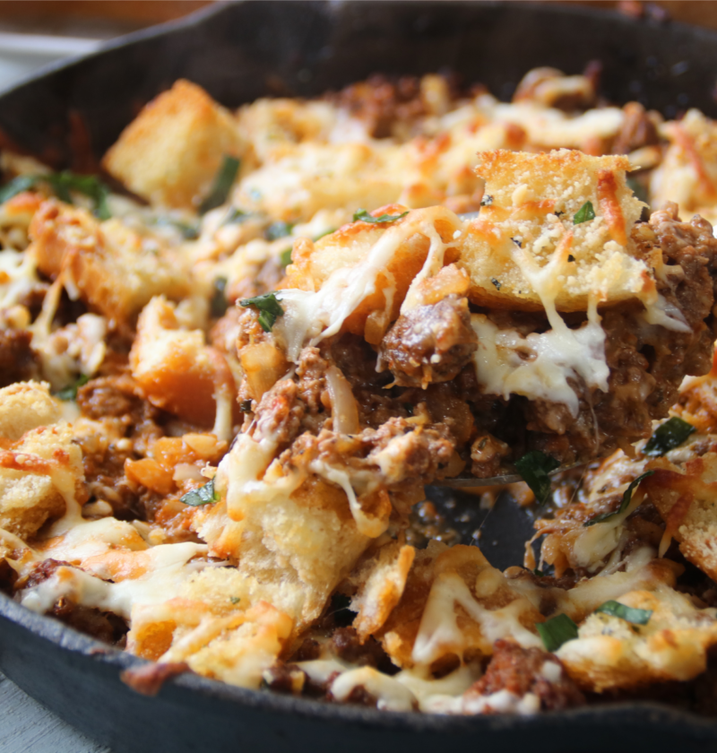 Meaty garlic bread bake with ground beef and melted cheese in a cast iron skillet