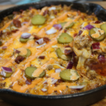 Whopper casserole in cast iron skillet with melted cheese and sauce drizzle