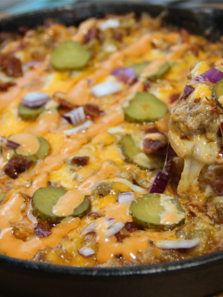 Whopper casserole in cast iron skillet with melted cheese and sauce drizzle