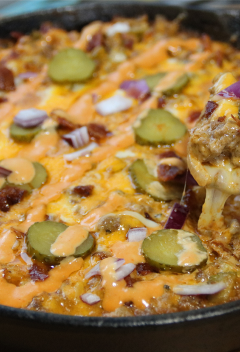 Whopper casserole in cast iron skillet with melted cheese and sauce drizzle