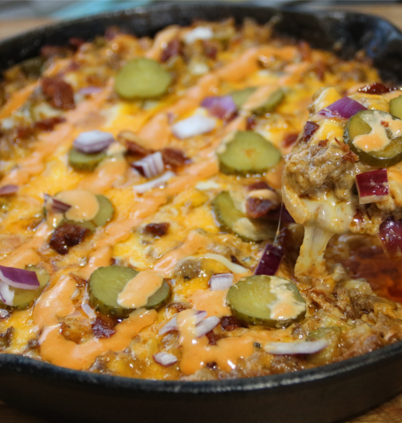 Whopper casserole in cast iron skillet with melted cheese and sauce drizzle