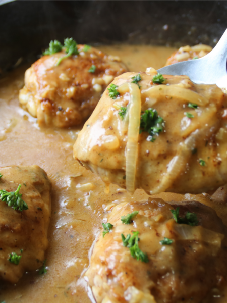 Old fashioned chicken and gravy supper with crispy chicken thighs in rich onion gravy served in a rustic skillet.