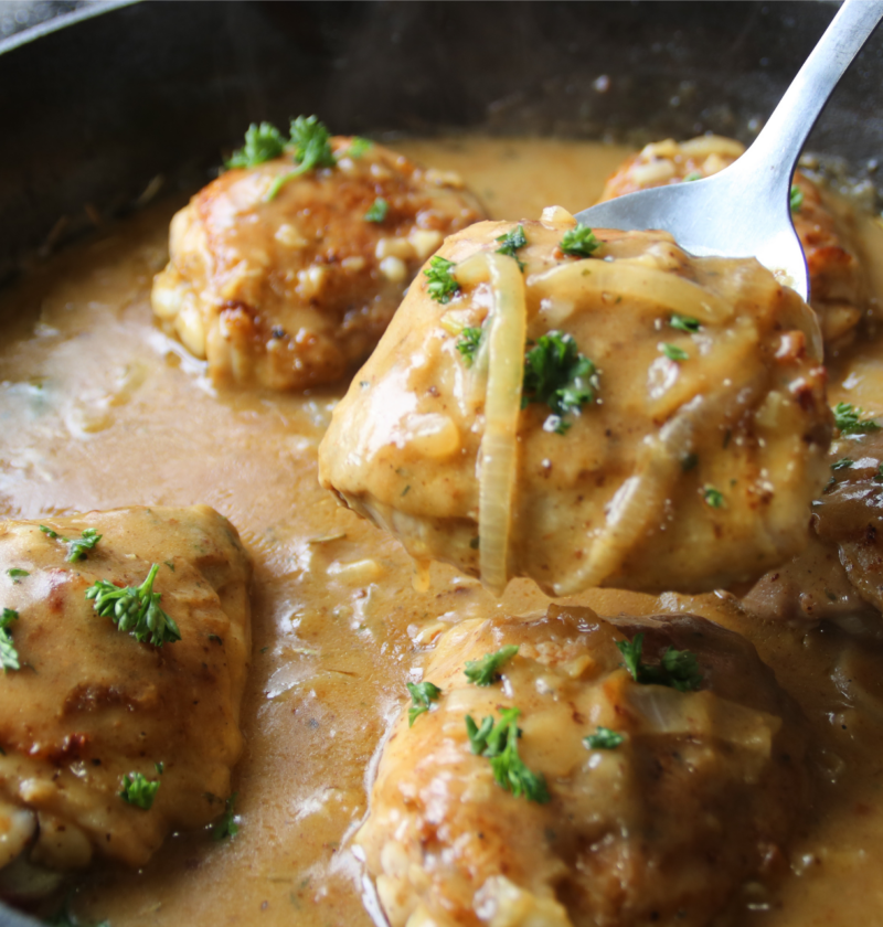 Old fashioned chicken and gravy supper with crispy chicken thighs in rich onion gravy served in a rustic skillet.
