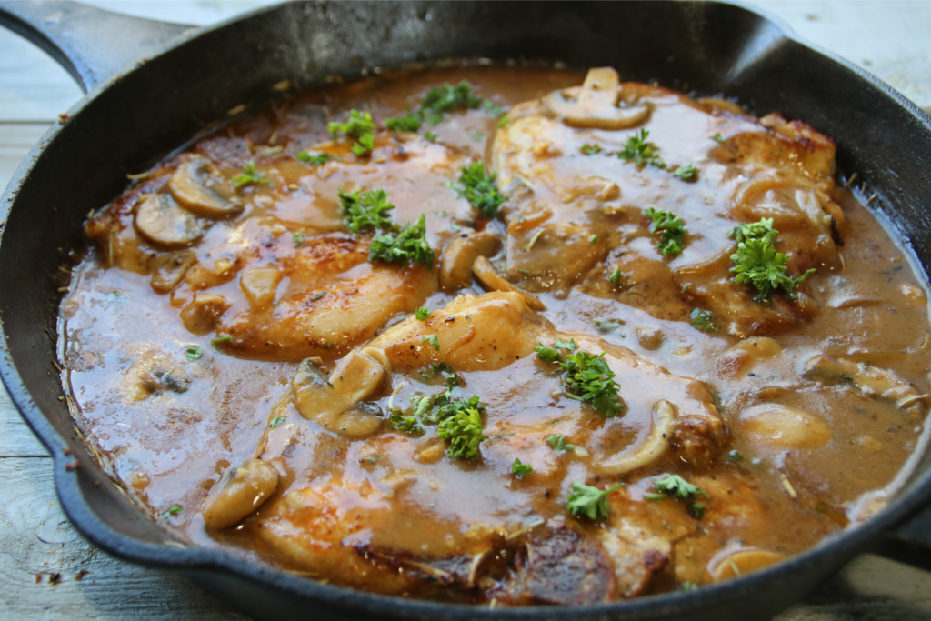 Smothered pork chops covered in rich onion mushroom gravy served with mashed potatoes and green beans in a hearty old-fashioned comfort supper.