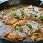 Smothered pork chops covered in rich onion mushroom gravy served with mashed potatoes and green beans in a hearty old-fashioned comfort supper.