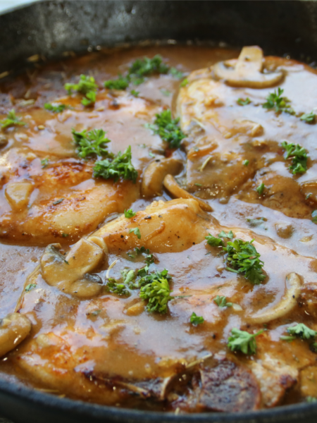 Smothered pork chops covered in rich onion mushroom gravy served with mashed potatoes and green beans in a hearty old-fashioned comfort supper.