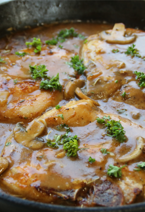 Smothered pork chops covered in rich onion mushroom gravy served with mashed potatoes and green beans in a hearty old-fashioned comfort supper.