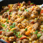 Family Table Sausage & Potato Supper served in a cast iron skillet with browned Italian sausage, tender potatoes, carrots, corn, melted cheddar cheese, and green onions.