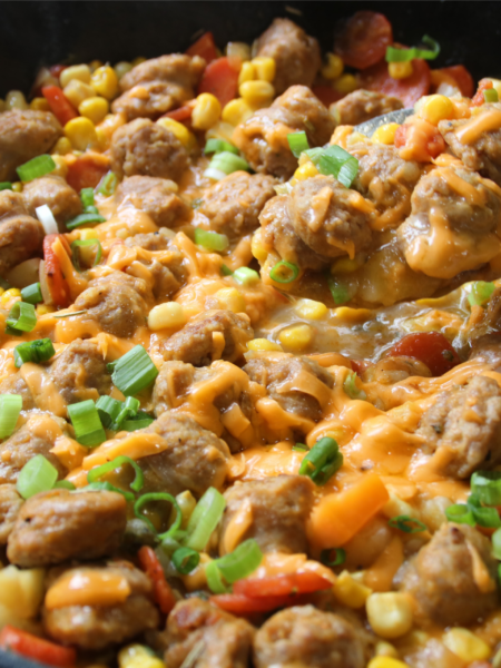 Family Table Sausage & Potato Supper served in a cast iron skillet with browned Italian sausage, tender potatoes, carrots, corn, melted cheddar cheese, and green onions.