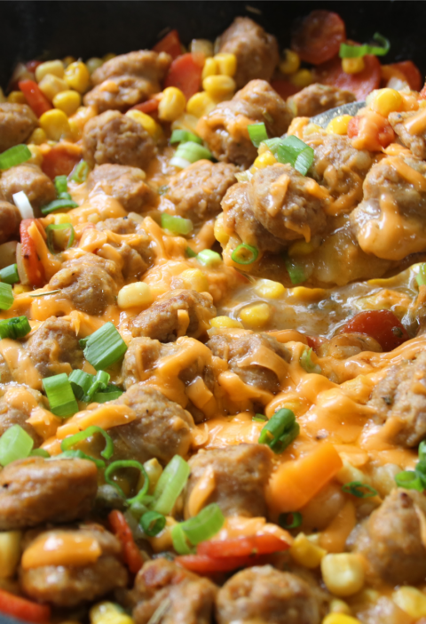 Family Table Sausage & Potato Supper served in a cast iron skillet with browned Italian sausage, tender potatoes, carrots, corn, melted cheddar cheese, and green onions.