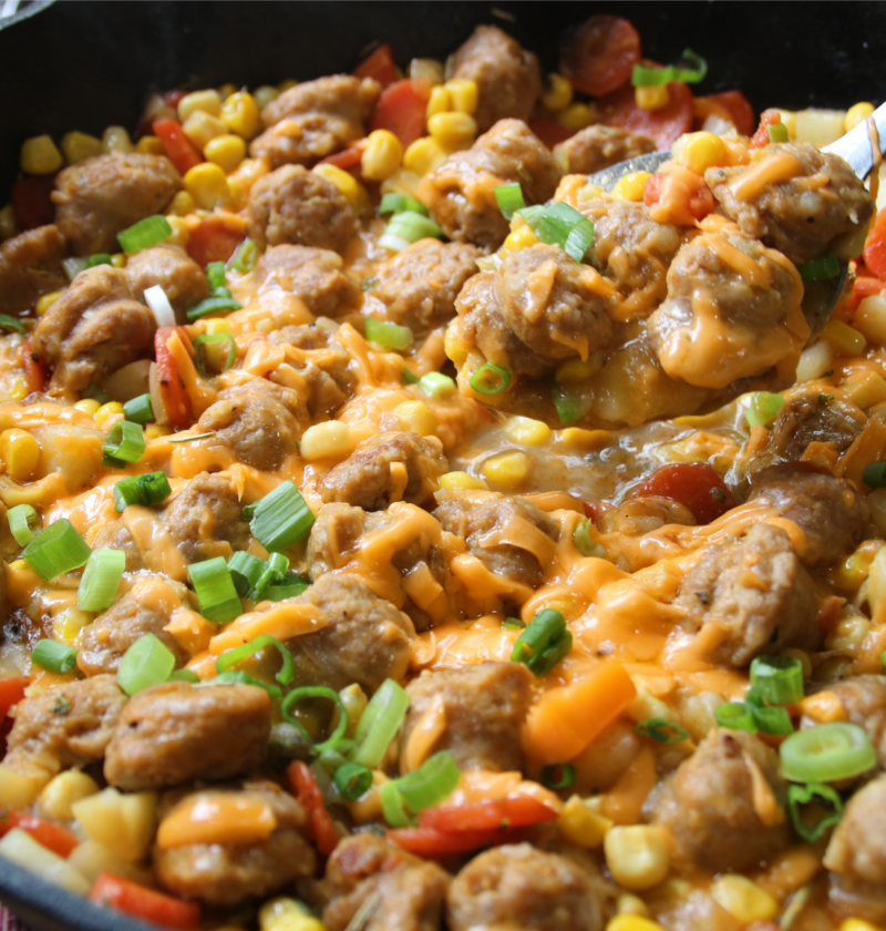 Family Table Sausage & Potato Supper served in a cast iron skillet with browned Italian sausage, tender potatoes, carrots, corn, melted cheddar cheese, and green onions.