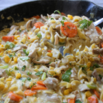 Creamy Chicken & Noodles Skillet served in a cast-iron skillet with tender chicken, wide egg noodles, carrots, corn, and rich homemade gravy.