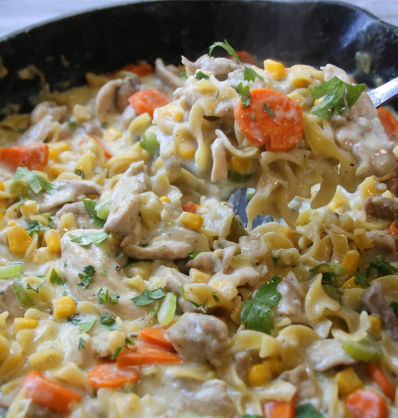 Creamy Chicken & Noodles Skillet served in a cast-iron skillet with tender chicken, wide egg noodles, carrots, corn, and rich homemade gravy.