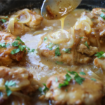 Old School Smothered Chicken with tender boneless chicken thighs simmered in a rich homemade onion gravy in a cast iron skillet.