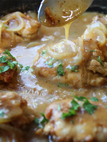 Old School Smothered Chicken with tender boneless chicken thighs simmered in a rich homemade onion gravy in a cast iron skillet.