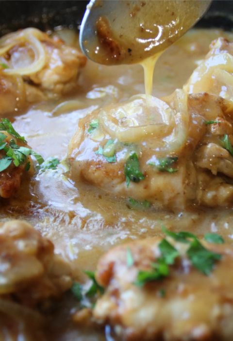 Old School Smothered Chicken with tender boneless chicken thighs simmered in a rich homemade onion gravy in a cast iron skillet.