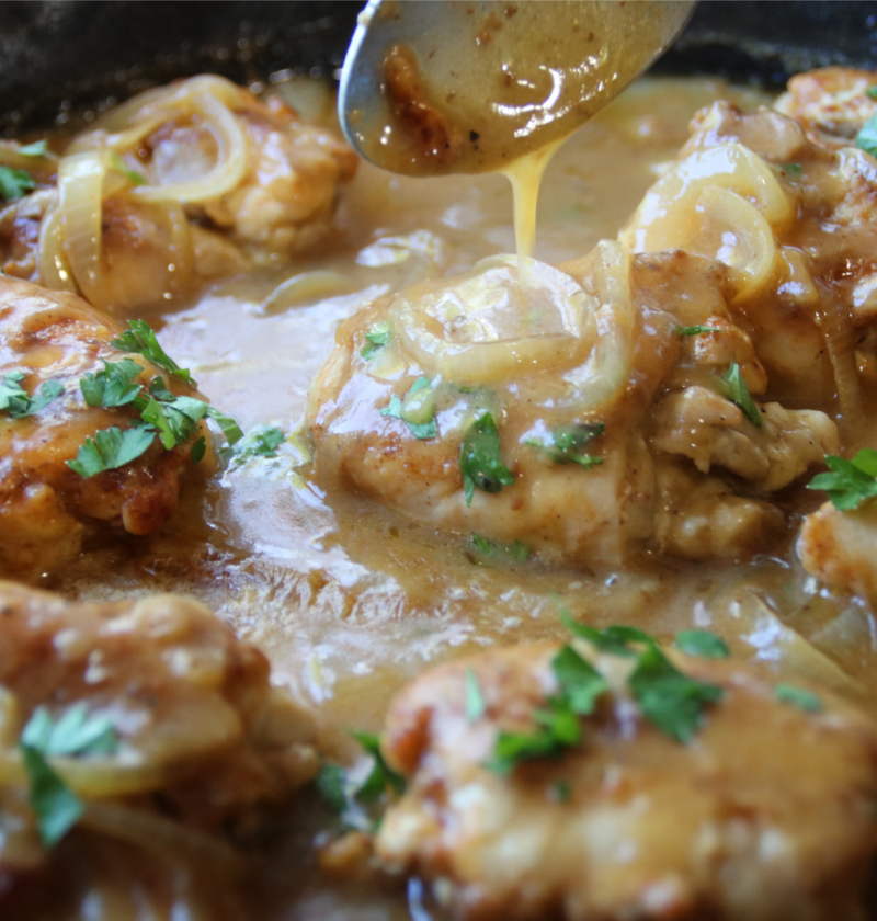 Old School Smothered Chicken with tender boneless chicken thighs simmered in a rich homemade onion gravy in a cast iron skillet.