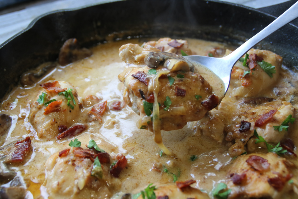 Old Time Creamy Chicken Skillet with tender chicken, crispy bacon, mushrooms, onions, and creamy Parmesan gravy in a cast-iron skillet.