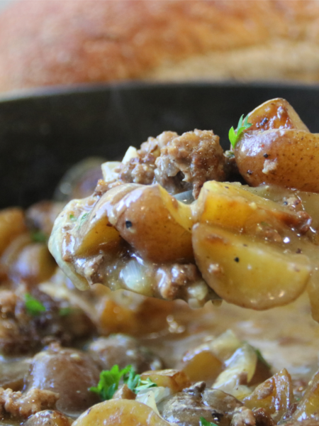 Old Time Ground Beef Magic with potatoes, sliced onions, and rich beef gravy in a cast iron skillet